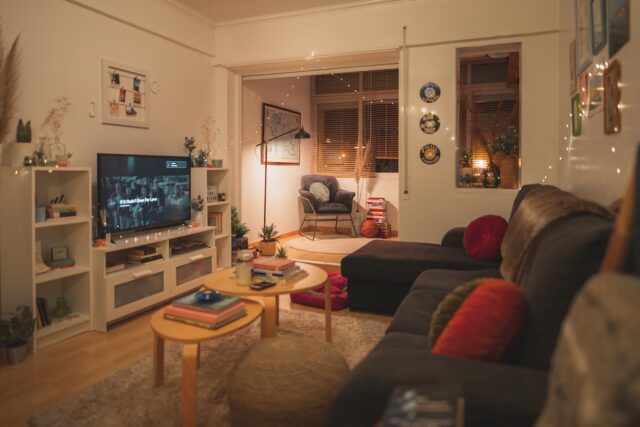 Een televisie staat aan in een warm verlichte woonkamer met een bank en een salontafel