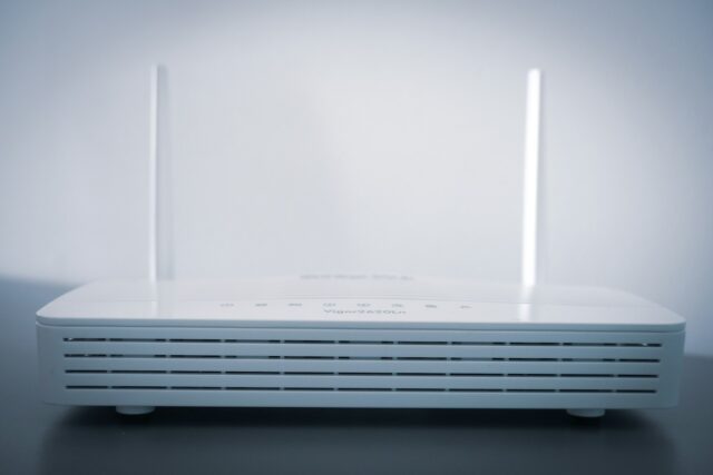 Een witte router met twee opstaande antennes staat op een tafel
